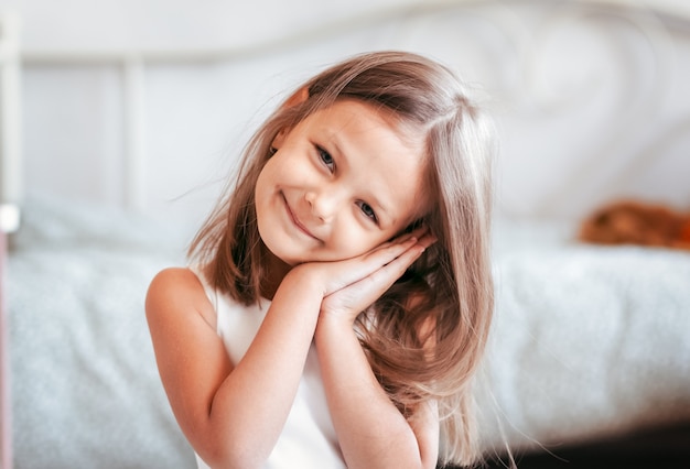 Portrait of a beautiful smiling girl in a light room. Close-up. A look at the camera