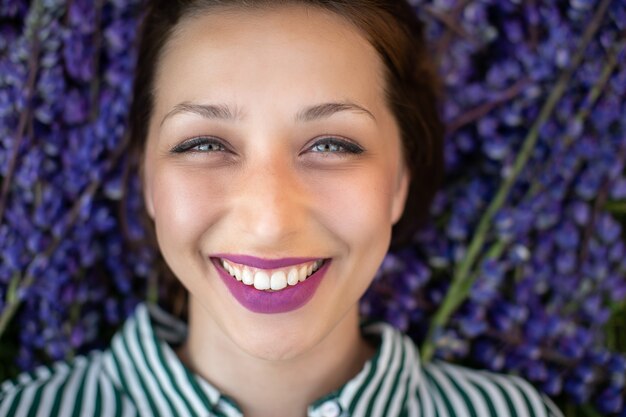 Foto ritratto di bella ragazza sorridente che guarda in avanti su sfondo di fiori selvatici