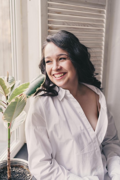 Photo portrait of a beautiful smiling girl with long dark hair in a white shirt, spa and wellness concept