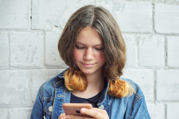 Portrait of beautiful smiling teenage girl of 14, 15 years old with smartphone