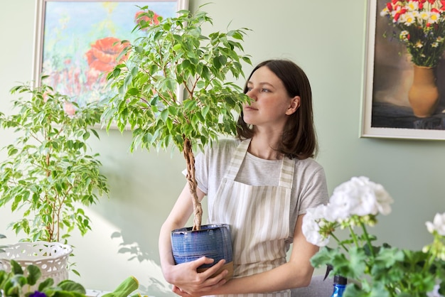 鉢植えの植物と美しい笑顔の10代の少女の肖像画。観葉植物の栽培と世話。趣味とレジャー、家庭菜園、都会のジャングル、鉢植えの友達のコンセプト