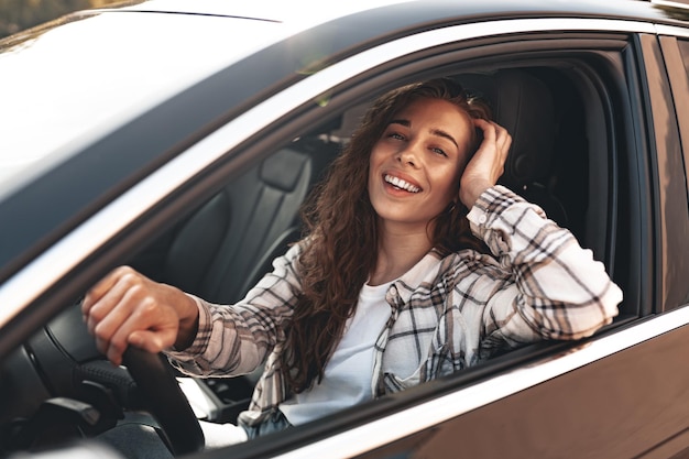 Portrait of a beautiful smiling woman in a car looking out of the window close up