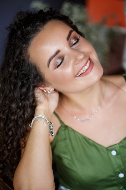 Portrait of a beautiful smiling woman of European appearance in a dress with curls hairstyle. Fashion and beauty