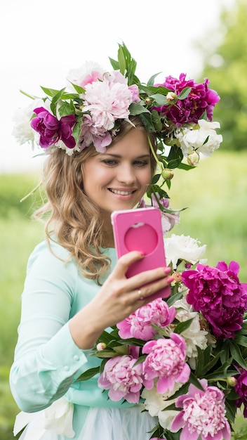 Portrait. Beautiful smiling woman wearing a wreath and a bouquet of peonies