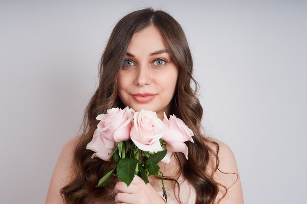 Portrait of a beautiful smiling woman with a bouquet of pink roses