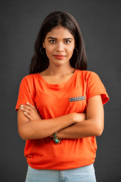 Portrait of a beautiful smiling young girl posing with handsfolded on gray background