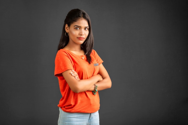 Portrait of a beautiful smiling young girl posing with handsfolded on gray background