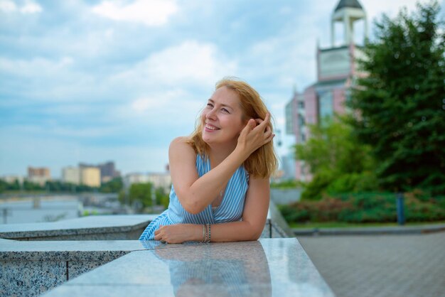 Портрет красивой улыбающейся молодой женщины в голубом платье Портрет на открытом воздухе на фоне голубого неба