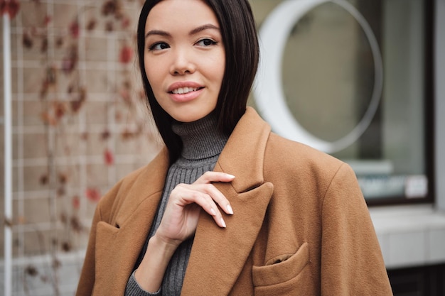 Photo portrait of beautiful stylish asian girl in coat dreamily looking away outdoor