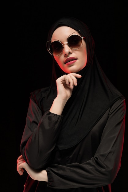 Portrait of beautiful stylish young muslim woman wearing black hijab and sunglasses fashion concept posing 