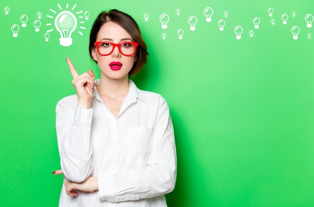 Portrait of beautiful surprised young woman in glasses on the wonderful studio green background