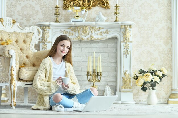 Portrait of beautiful teen girl sitting on floor near vintage armchair