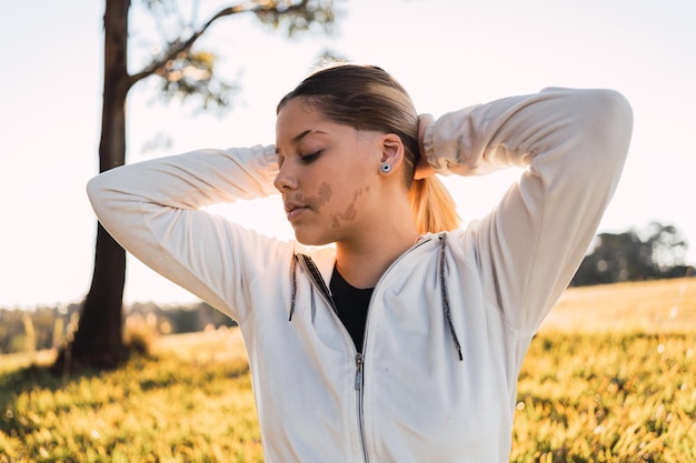 Photo portrait of beautiful teenage girl with a birthmark on her face with her eyes closed at sunset.