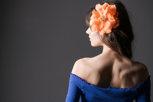 Portrait beautiful and tender girl with flower in her hair posing in a blue