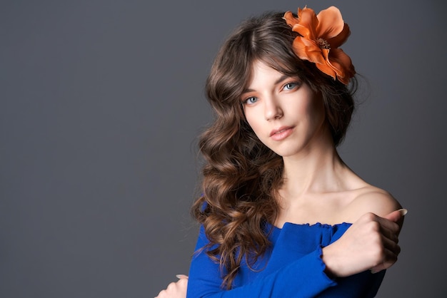 Portrait beautiful and tender girl with flower in her hair posing in a blue