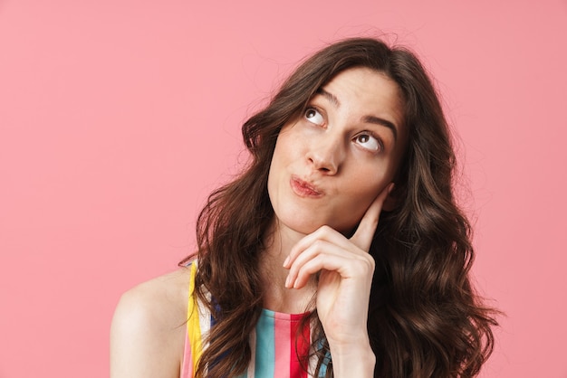 Portrait of beautiful thinking cute woman posing isolated over pink wall