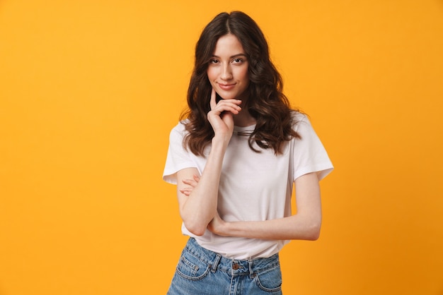 Portrait of beautiful thinking pleased young cute woman posing isolated over yellow wall.