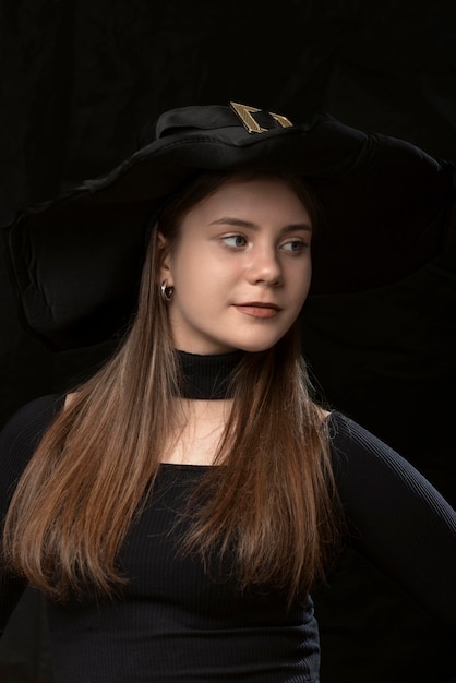 Portrait of beautiful toung woman in black widebrimmed hat Stylish young lady Vertical frame Modern witch Halloween