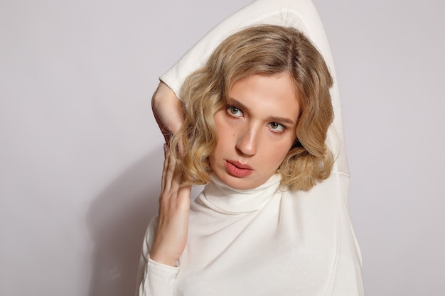 Portrait of beautiful transgender woman with blond hair over gray background