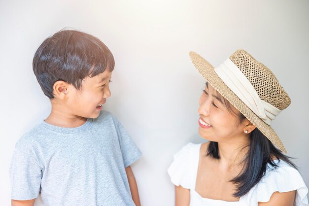 Ritratto bella viaggiatrice asiatica madre in abito bianco cappello di paglia e figlio in camicia grigia gode di relax sorriso svago al resort in vacanza sulla spiaggia tropicale