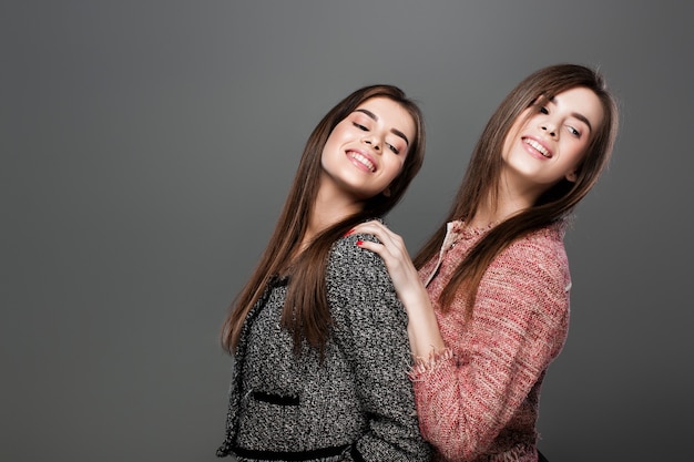 Portrait of beautiful twins women with  natural make-up and long hair. fashion