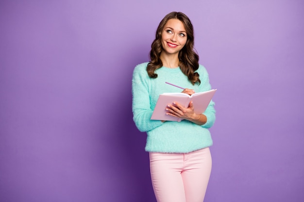 portrait of beautiful wavy lady hold planner write essay imagination flight look empty space responsible student wear pastel fuzzy sweater pink trousers.