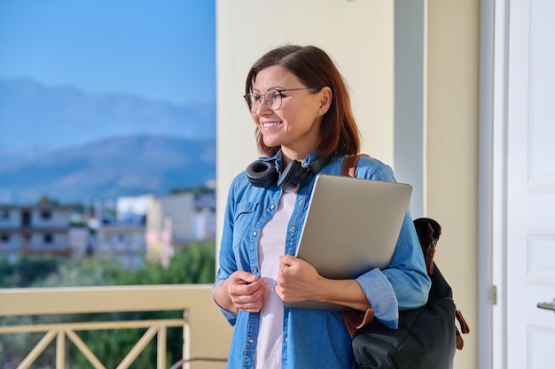 Portrait of beautiful woman 40s age with backpack laptop headphones outdoor