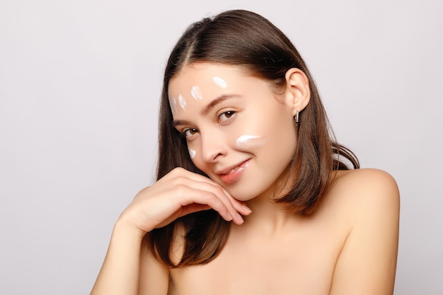 Portrait of beautiful woman applying face cream