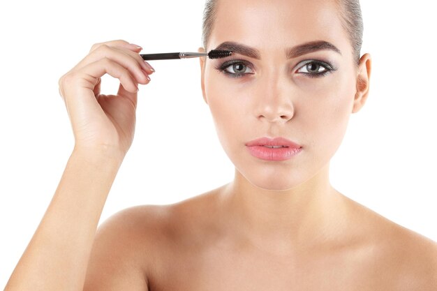 Photo portrait of beautiful woman applying stylish makeup with brush on white background