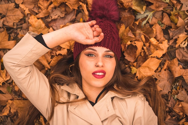 Portrait of a beautiful woman in autumn lying on brown leaves in a forest