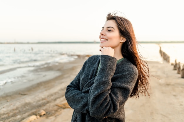 Portrait of a beautiful woman on the beach on sunset relaxing and smiling