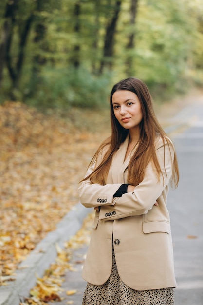 Ritratto di una bella donna in un cappotto beige che cammina in un parco autunnale