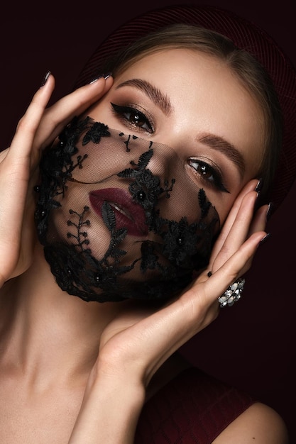 Portrait of a beautiful woman in a black lace mask and classic makeup Mask mode during the covid pandemic