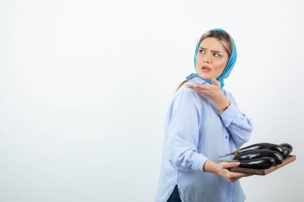 Portrait of beautiful woman in blue shawl holding eggplants