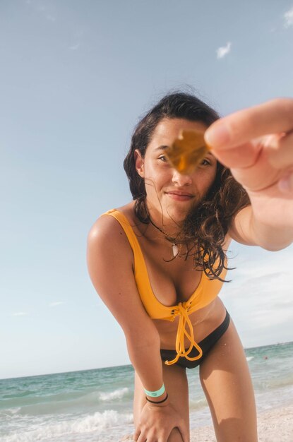 Portrait of beautiful woman broken glass while standing at beach against sky