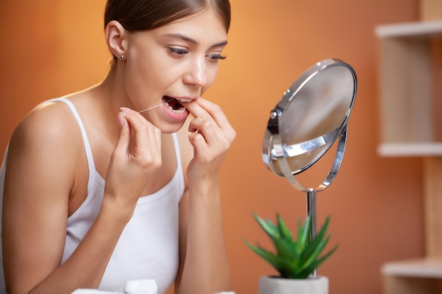 Portrait of beautiful woman cleaning teeth with dental floss