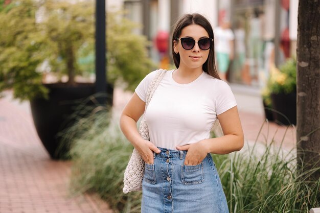 Photo portrait of beautiful woman in denim style walking in an open shopping center