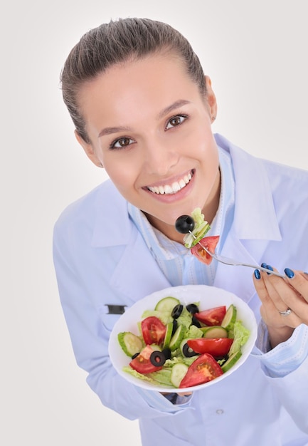 Portrait of a beautiful woman doctor holding a plate with fresh vegetables Woman doctors