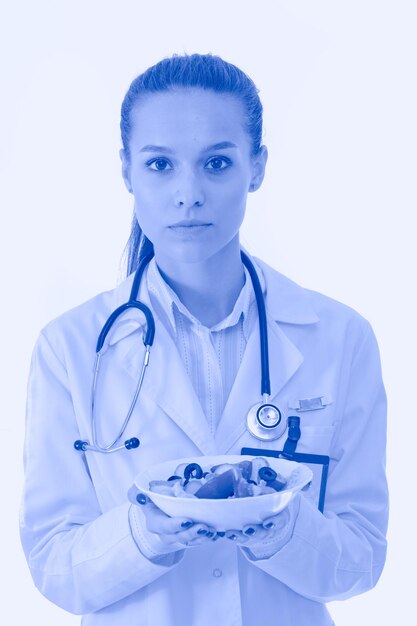 Portrait of a beautiful woman doctor holding a plate with fresh vegetables woman doctors