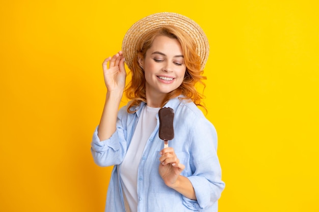 Portrait of beautiful woman eating ice cream on orange yellow background Girl in summer hat eating