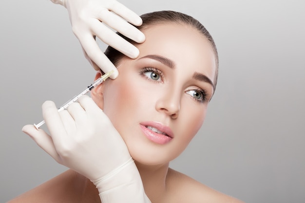 Free Photo  Beautiful young woman getting botox cosmetic injection in her  face.