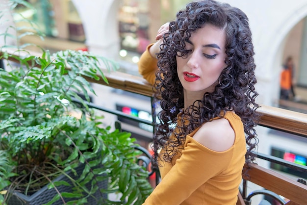 Portrait of a beautiful woman at the green houseplant on the balcony