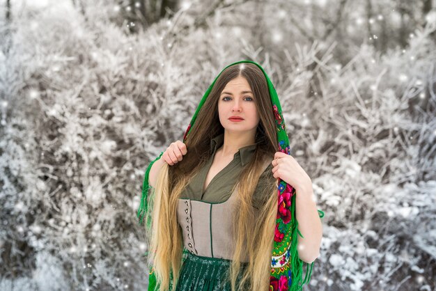 Portrait of beautiful woman in green shawl in winter forest