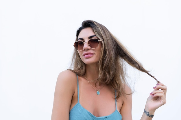 Portrait of beautiful woman in green summer dress on white background natural daylight wearing sunglasses smiling excited