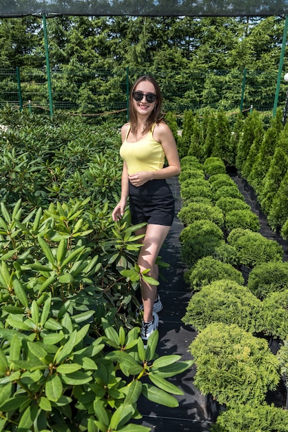 Portrait of beautiful woman in greenhouse between colorful flowers. Lifestyle