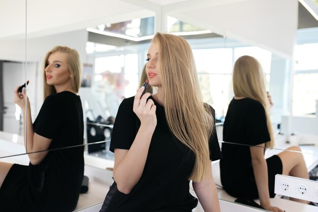 Photo portrait of a beautiful woman her lips are painted with pink lipstick looking in the mirror