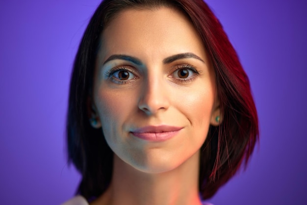 Portrait of beautiful woman in her s with short hair looking at camera against purple studio