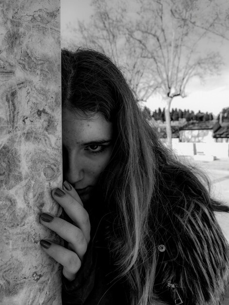 Photo portrait of beautiful woman hiding by wall