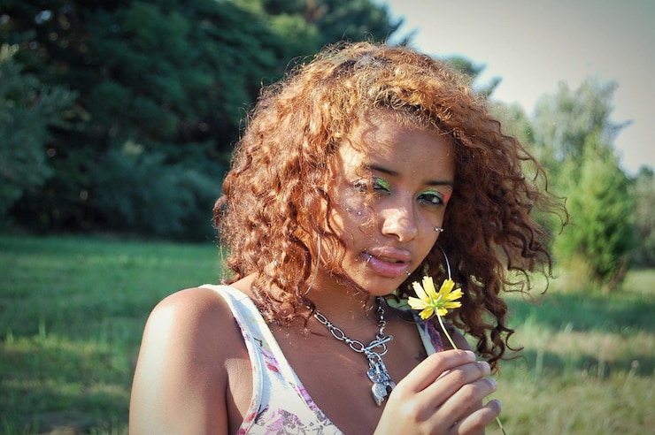 Photo portrait of beautiful woman holding flower and standing on field