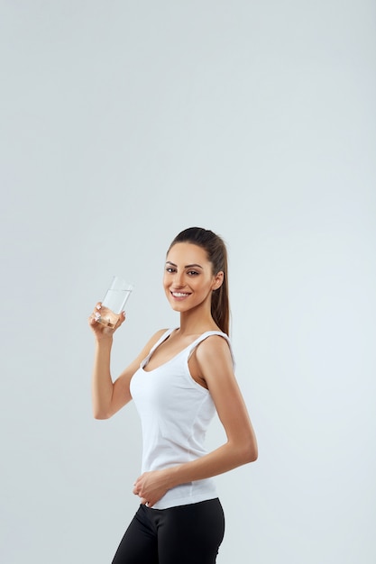 Portrait of beautiful woman holds glass of water. Drink water. Girl with glass of water. Diet concept